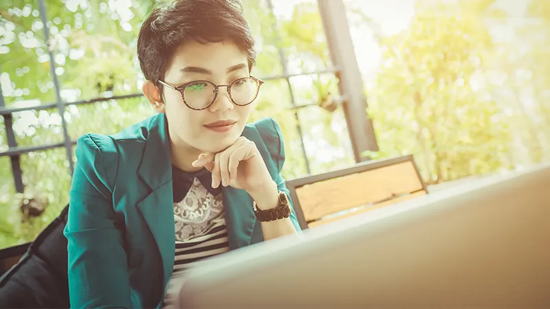 A professional woman studying on her laptop in a bright café setting, reflecting on whether it is too late to change career or upskill in Singapore.