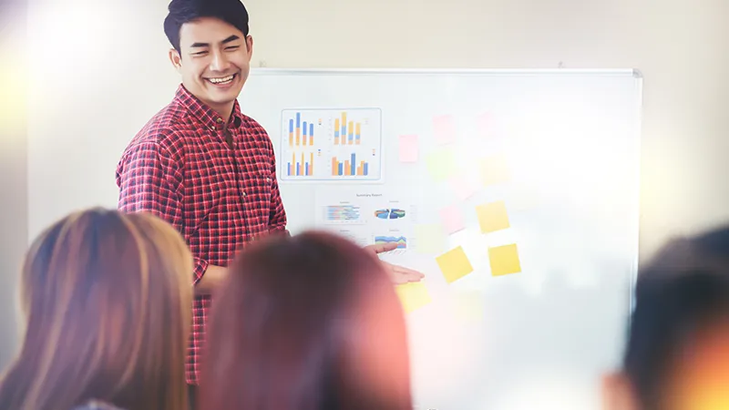A trainer leading a workshop with charts and sticky notes on a board, symbolising learning opportunities for those asking if it is too late to change career or upskill