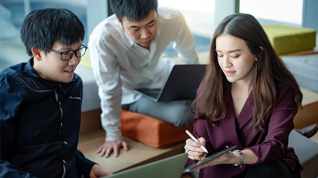 A group of adult learners collaborating on a project, illustrating the hands-on learning approach of SkillsFuture SCTP courses.