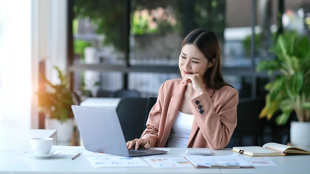 A woman studying on her laptop in a bright workspace, reflecting the flexibility and convenience of learning through SkillsFuture SCTP courses.